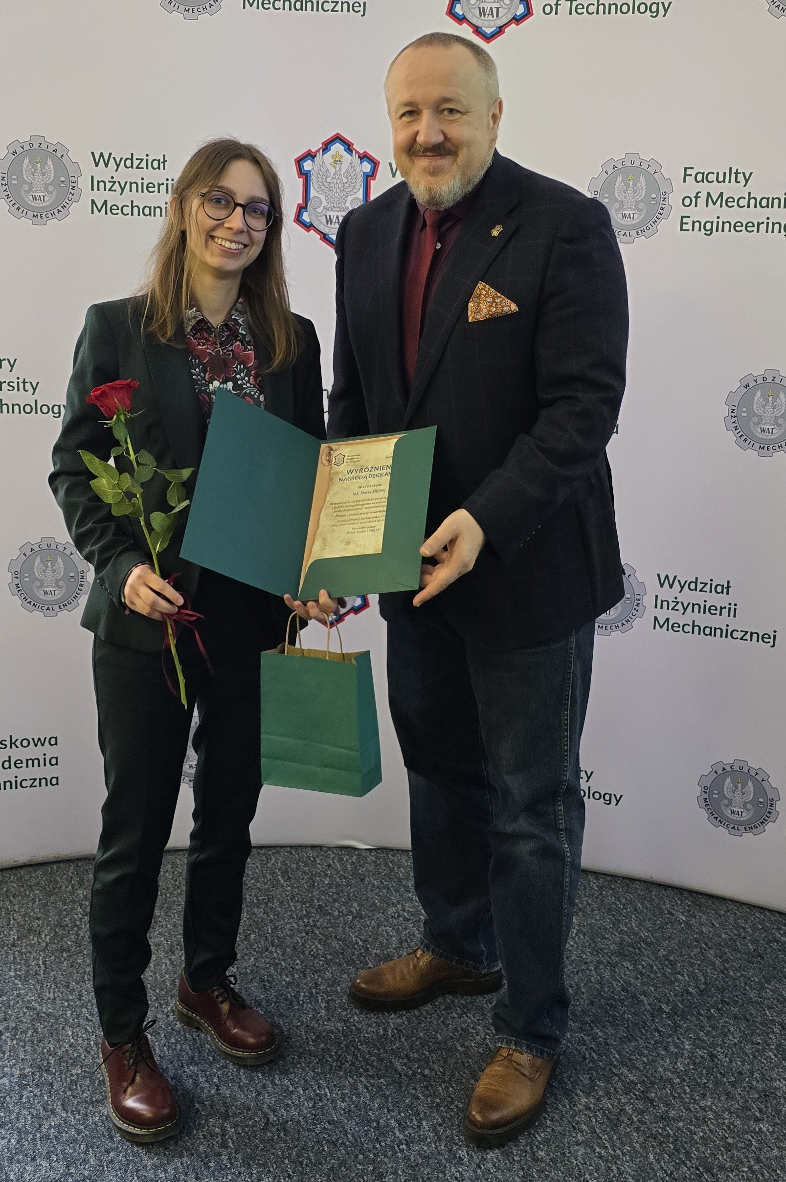 Fot. 3. Daria Siejka i dziekan Jerzy Małachowski na tle ścianki wydziałowej z logiem WIM WAT.